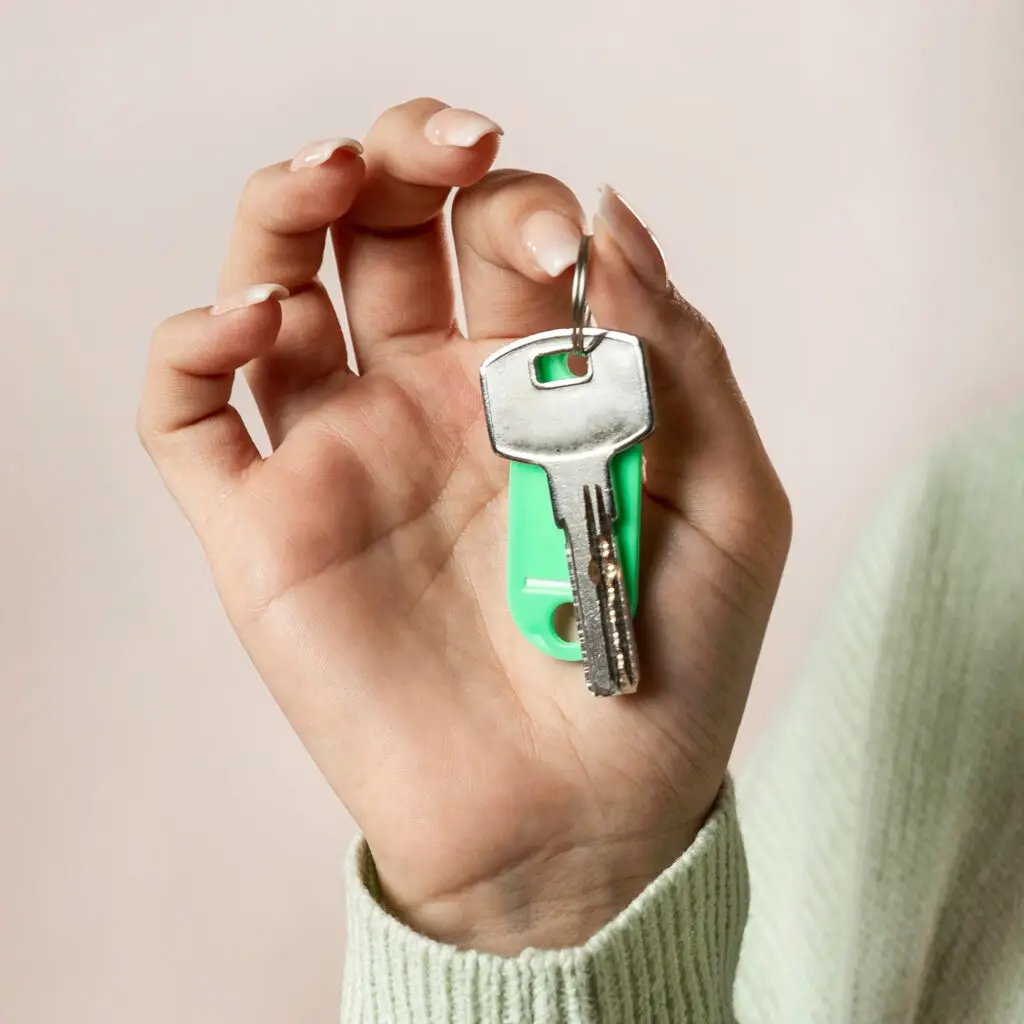 Close-up of a hand holding house keys, symbolizing homeownership and real estate success.