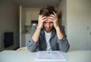 Frustrated homebuyer in Dubai holding his head while looking at mortgage documents, struggling to decide between fixed and variable interest rates.
